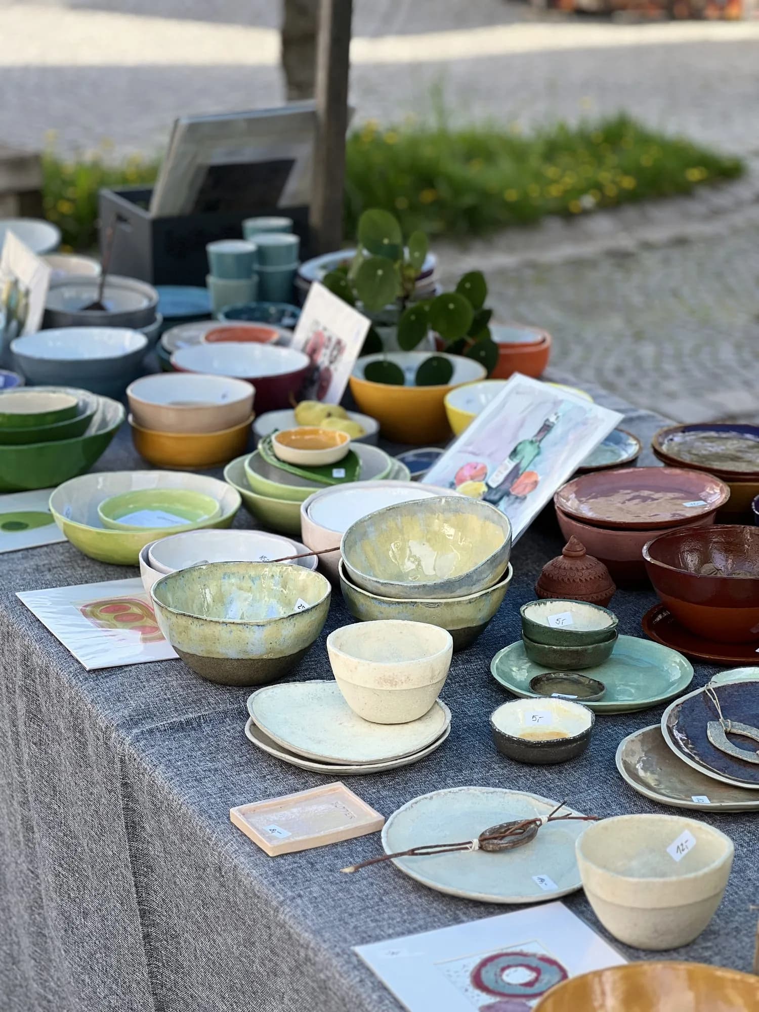 Marktstand im Freien mit einer großen Auswahl an bunt glasierten Keramikschalen und -tellern.