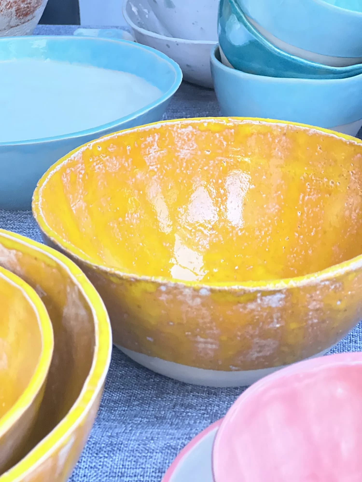 Nahaufnahme einer Keramikschale mit gelber Glasur, im Hintergrund weitere blaue Schalen.