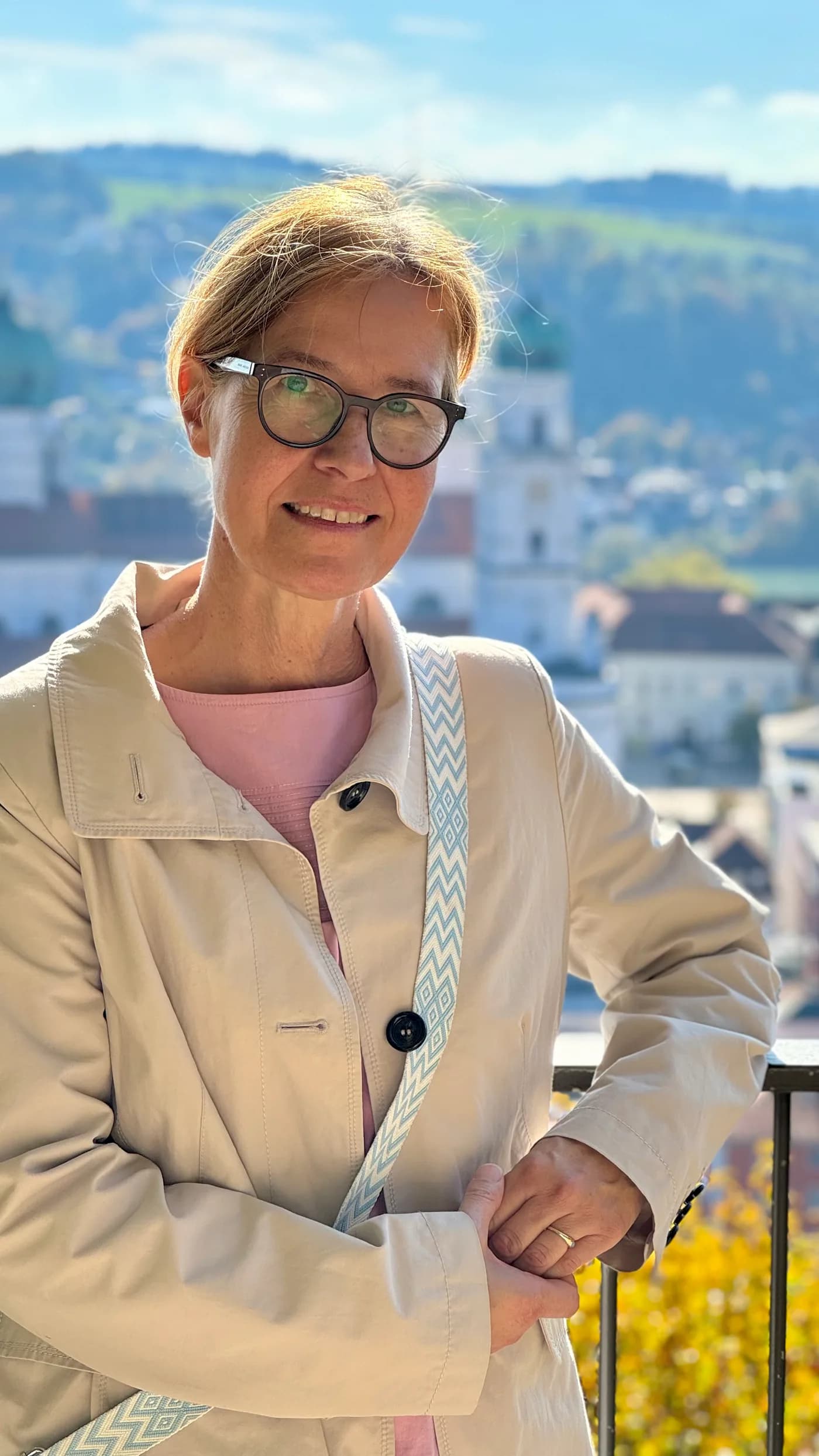Beatrix Diedenhofen lächelt in die Kamera, im Hintergrund eine Voralpenlandschaft mit Kirchturm